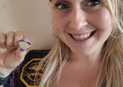 lady smiling and holding up her pin badge